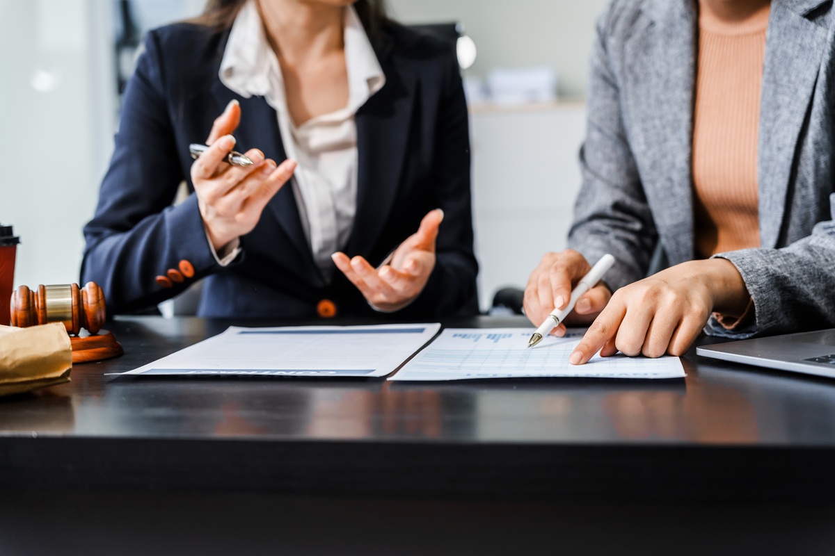 Two,Female,Lawyers,In,Business,Suits,Meet,At,Wooden,Desk,